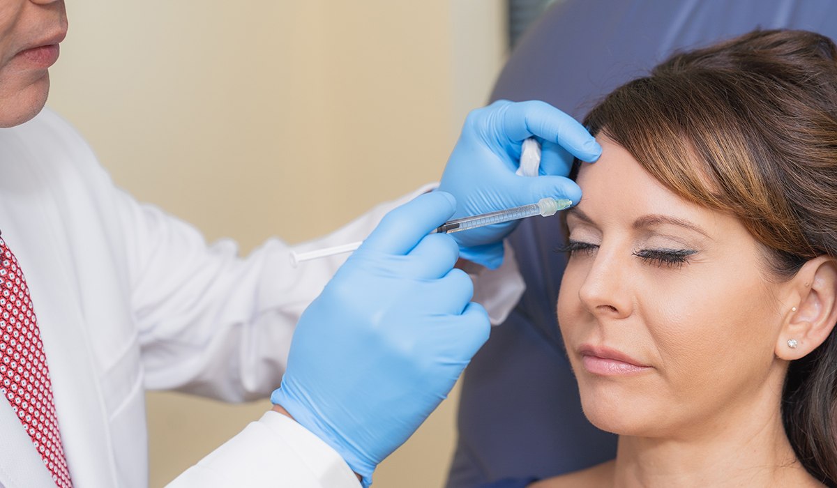 Dr. Vu Demonstrating Injecting A Dermal Filler Into Patient's Forehead